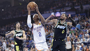 Oklahoma City Thunder guard Shai Gilgeous-Alexander drives to the basket beside Indiana Pacers guard Tyrese Haliburton. 