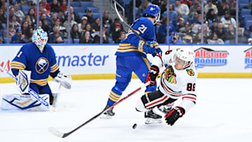 Nov 21, 2025; Buffalo, New York, USA; Chicago Blackhawks center Teuvo Teravainen (86) is knocked off his skates by Buffalo Sabres defenseman Conor Timmins (21) in front of goaltender Ukko-Pekka Luukkonen (1) in the third period at KeyBank Center. Mandatory Credit: Mark Konezny-Imagn Images