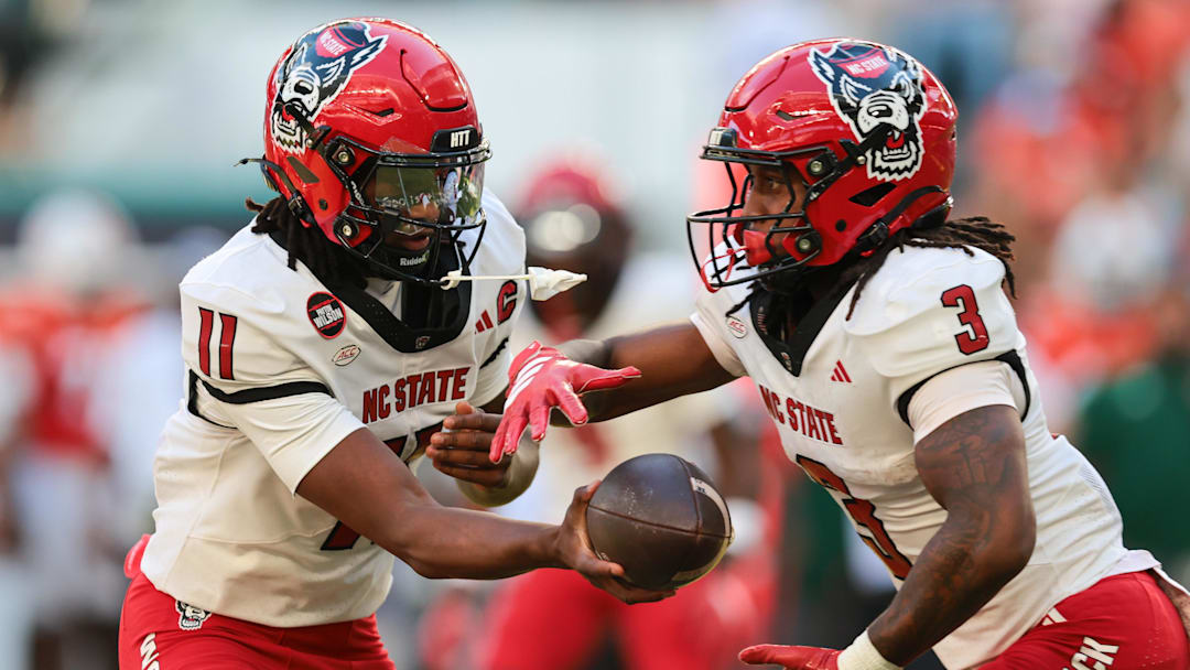 Nov 15, 2025; Miami Gardens, Florida, USA; NC State Wolfpack quarterback CJ Bailey (11) hands off the football to running back Hollywood Smothers (3) during the first quarter at Hard Rock Stadium. Mandatory Credit: Sam Navarro-Imagn Images