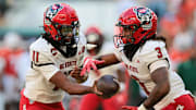 Nov 15, 2025; Miami Gardens, Florida, USA; NC State Wolfpack quarterback CJ Bailey (11) hands off the football to running back Hollywood Smothers (3) during the first quarter at Hard Rock Stadium. Mandatory Credit: Sam Navarro-Imagn Images