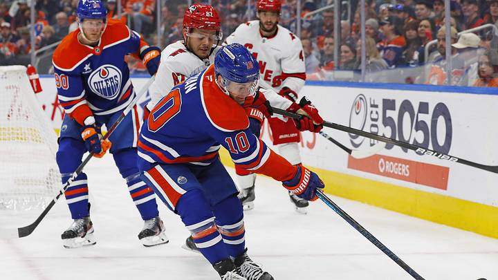 Oct 22, 2024; Edmonton, Alberta, CAN; Edmonton Oilers forward Derek Ryan (10) and Carolina Hurricanes forward Jesperi Kotkaniemi (82) battle along the boards for a loose puck  during the third period at Rogers Place. Mandatory Credit: Perry Nelson-Imagn Images