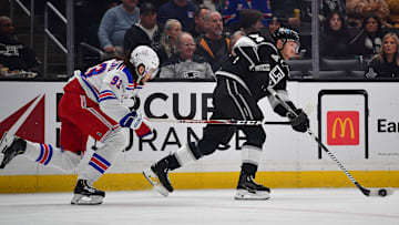 Jan 20, 2024; Los Angeles, California, USA; Los Angeles Kings defenseman Vladislav Gavrikov (84) moves the puck ahead of New York Rangers center Mika Zibanejad (93) durng the first period at Crypto.com Arena. Mandatory Credit: Gary A. Vasquez-Imagn Images