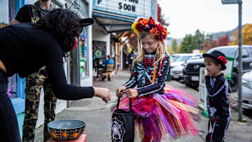 Two kids dressed in Halloween costumes are seen getting candy