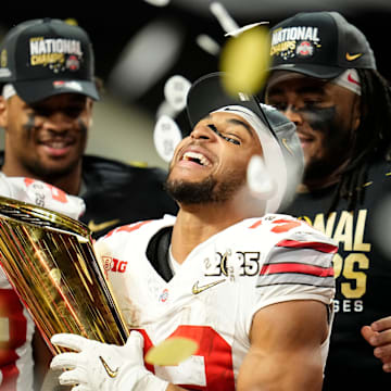 Ohio State running back TreVeyon Henderson (32) holds the national championship trophy after his team's defeat of Notre Dame in the College Football Playoff title game at Mercedes-Benz Stadium in Atlanta on Jan. 21, 2025.