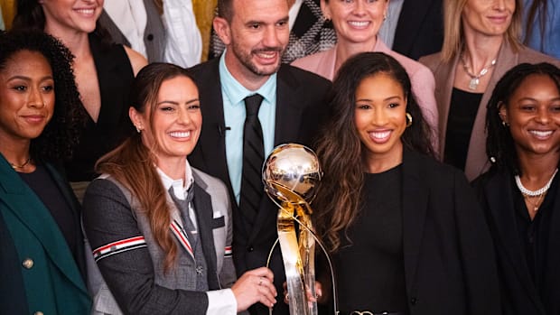 Former Gotham FC team captain Ali Krieger, middle left, and forward Midge Purce hold the NSWL Championship trophy to pose.