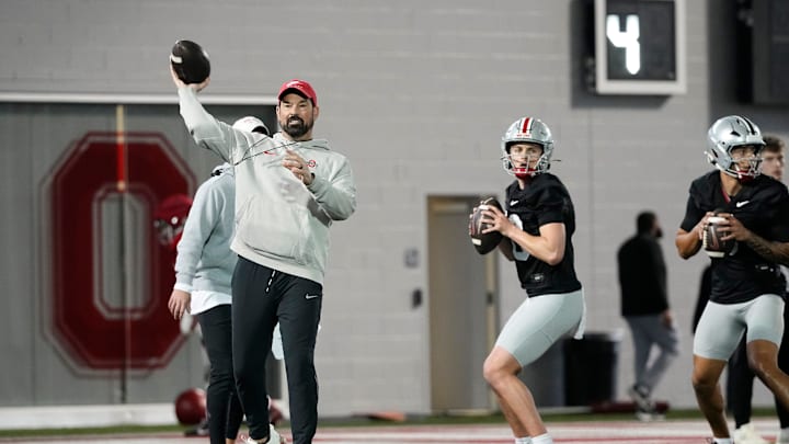 Ohio State Buckeyes head coach Ryan Day throws alongside quarterbacks Julian Sayin (10) and Tavien St. Clair (9) during spring football practice at the Woody Hayes Athletic Center in Columbus on March 19, 2025.