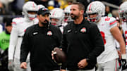 Ohio State Buckeyes offensive coordinator Brian Hartline and head coach Ryan Day leads warm ups during the NCAA football game against the Michigan Wolverines at Michigan Stadium in Ann Arbor, Mich. on Nov. 29, 2025. Ohio State won 27-9.