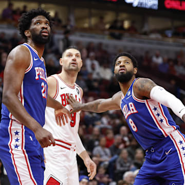 Dec 8, 2024; Chicago, Illinois, USA; Philadelphia 76ers center Joel Embiid (21) and forward Paul George (8) defend against Chicago Bulls center Nikola Vucevic (9) during the first half at United Center. Mandatory Credit: Kamil Krzaczynski-Imagn Images