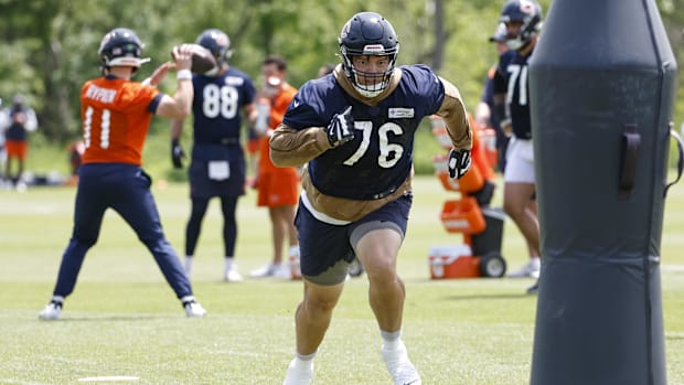 Bears guard Teven Jenkins (blue jersey) runs to a pad to train during camp.