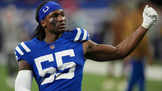 Indianapolis Colts defensive end Isaiah Land (blue jersey w/ white numbers) stretches before a game. 