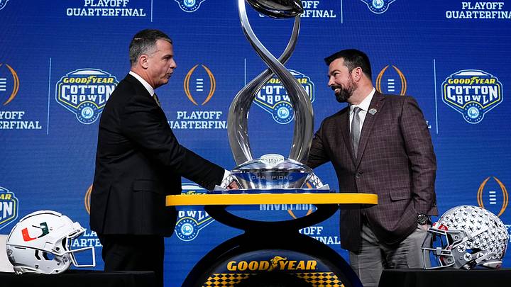 Ohio State Buckeyes head coach Ryan Day, right, and Miami (FL) Hurricanes head coach Mario Cristobal shake hands behind the Field Scovell Trophy after talking to media during a Cotton Bowl press conference at AT&T Stadium in Arlington, Texas prior to their College Football Playoff quarterfinal matchup on Dec. 30, 2025.