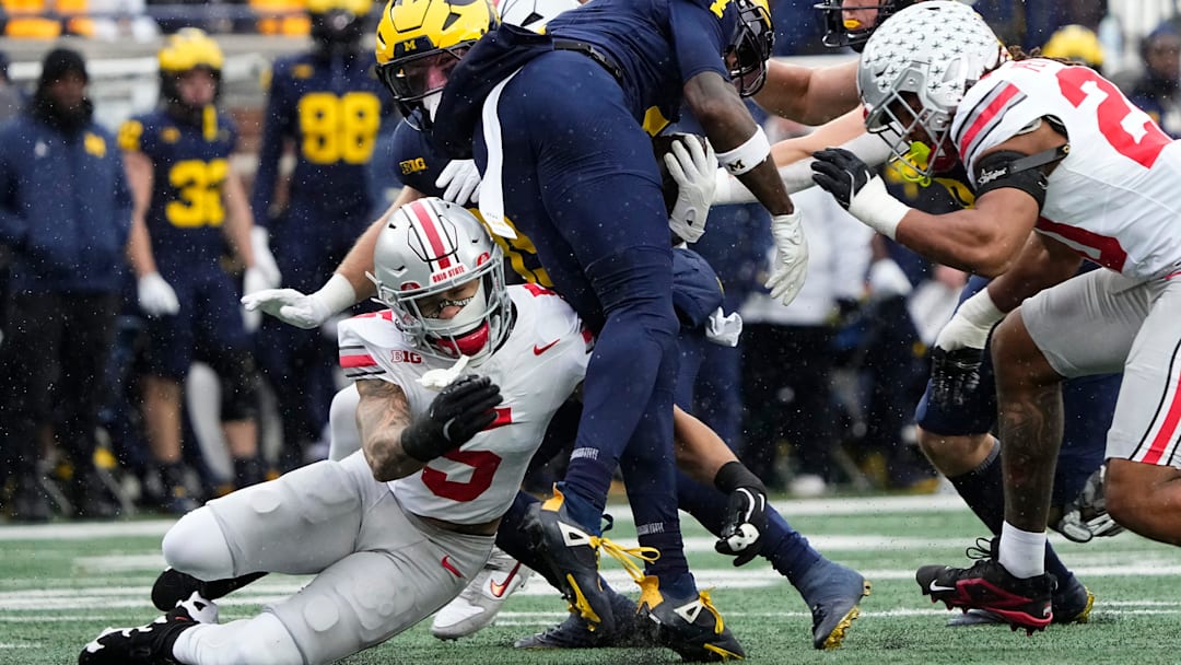 Ohio State Buckeyes cornerback Aaron Scott Jr. (5) tackles Michigan Wolverines wide receiver Andrew Marsh (4) during the NCAA football game at Michigan Stadium in Ann Arbor, Mich. on Nov. 29, 2025. Ohio State won 27-9.