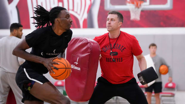 Basketball player defended by coach with pad.