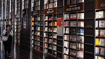 A woman seen walking past a bookshelf at the Zhongshuge...