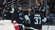 Kraken defenseman Justin Schultz forward Oliver Bjorkstrand and forward Yanni Gourde celebrate an overtime goal against the Flyers.