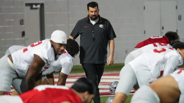 Head coach walks toward players during stretches.