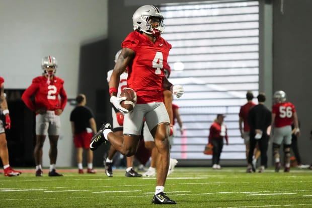 Wide receiver runs with football in practice.