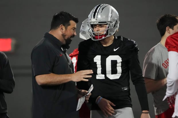 Quarterback speaks with head coach at practice.