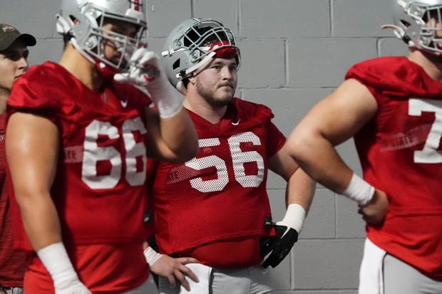 Football player waits with hands on hips between drills.