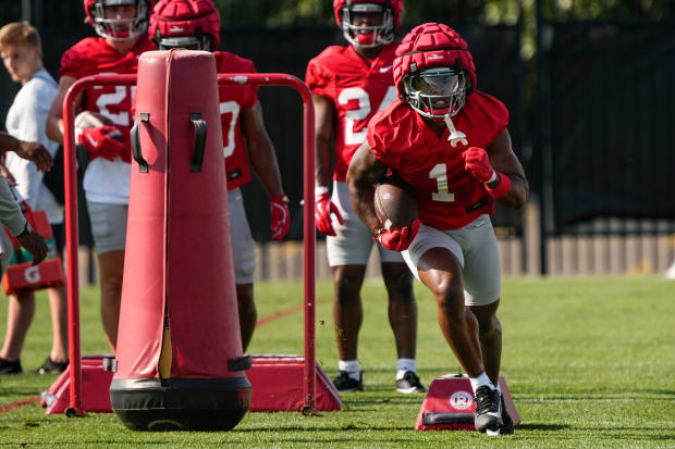 Running back carries football in drill during practice.