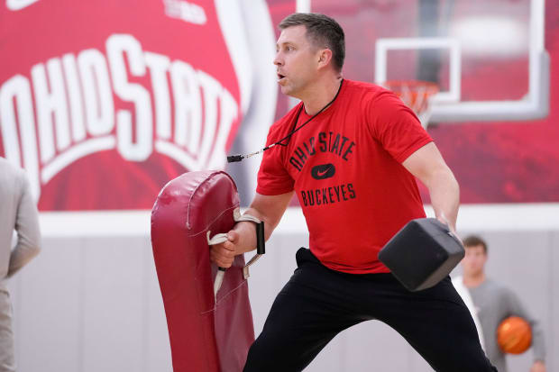 Head coach holds pads during practice.