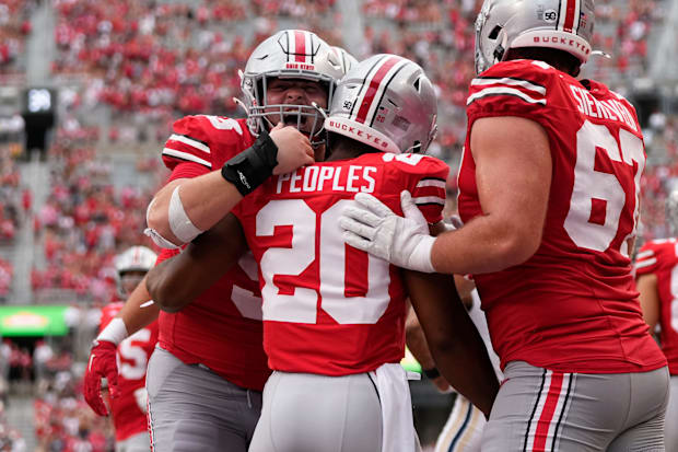 Offensive linemen celebrate with running back after touchdown.