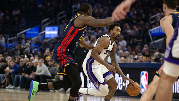 Mar 13, 2025; San Francisco, California, USA; Sacramento Kings guard Malik Monk (0) dribbles past Golden State Warriors forward Draymond Green (23) during the first quarter at Chase Center. Mandatory Credit: D. Ross Cameron-Imagn Images