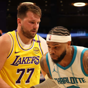 Feb 19, 2025; Los Angeles, California, USA: Charlotte Hornets forward Miles Bridges (0) drives against Los Angeles Lakers guard Luka Doncic (77) during the third quarter at Crypto.com Arena. Mandatory Credit: Jason Parkhurst-Imagn Images
