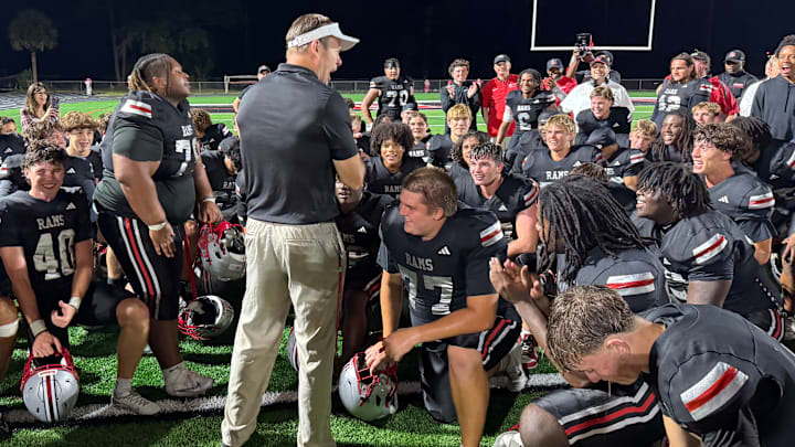 Lake Mary football coach Scott Perry, center standing, applauds his team after the Rams beat defending Class 7A state champ Venice, 31-26, in a state semifinal on Friday, Dec. 5.