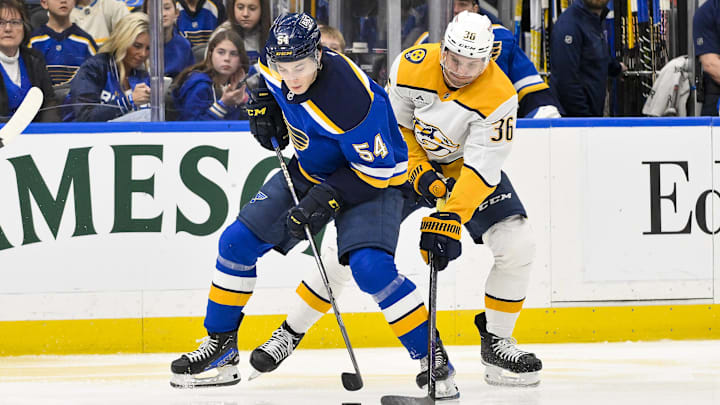 Mar 23, 2025; St. Louis, Missouri, USA;  St. Louis Blues center Dalibor Dvorsky (54) controls the puck as Nashville Predators left wing Cole Smith (36) defends during the second period at Enterprise Center. Mandatory Credit: Jeff Curry-Imagn Images
