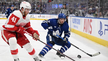 Toronto Maple Leafs forward Alexander Kerfoot (15) shoots the puck around the boards as Detroit Red Wings defender Jared McIsaac puts on the pressure.