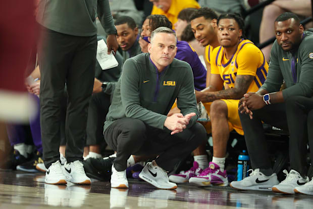 LSU basketball coach Matt McMahon crouches on the sideline.