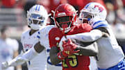 Oct 5, 2024; Louisville, Kentucky, USA;  Louisville Cardinals running back Isaac Brown (25) tries to break from the tackle of Southern Methodist Mustangs cornerback Deuce Harmon (7) during the second half at L&N Federal Credit Union Stadium. Mandatory Credit: Jamie Rhodes-Imagn Images