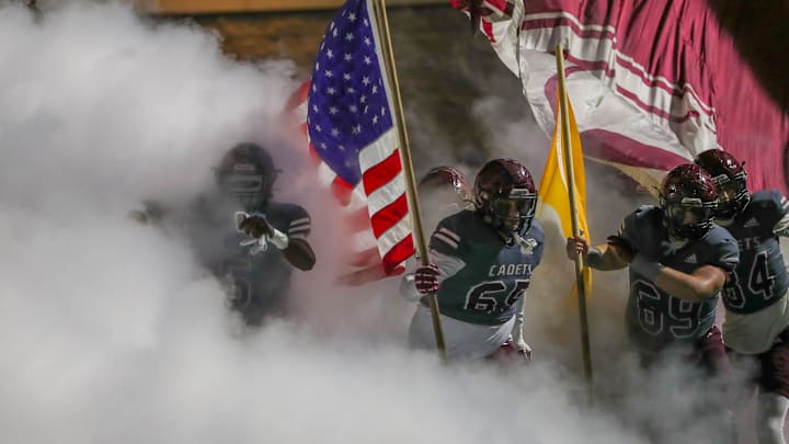 Players from Benedictine run onto the field through a cloud of smoke during the State 4-A semifinals on Friday, December 5, 2025 at Memorial Stadium.