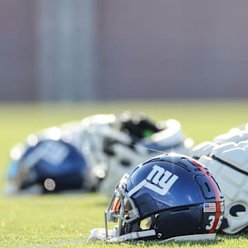 New York Giants helmets rest on the grass field during 2024 training camp at the Quest Diagnostics Training Facility.   