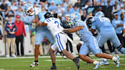 Nov 22, 2025; Chapel Hill, North Carolina, USA; North Carolina Tar Heels quarterback Gio Lopez (7) is hit after a pass by Duke Blue Devils defensive back Caleb Weaver (3) during the first half at Kenan Stadium. Mandatory Credit: William Howard-Imagn Images