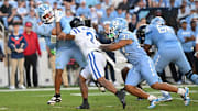 Nov 22, 2025; Chapel Hill, North Carolina, USA; North Carolina Tar Heels quarterback Gio Lopez (7) is hit after a pass by Duke Blue Devils defensive back Caleb Weaver (3) during the first half at Kenan Stadium. Mandatory Credit: William Howard-Imagn Images