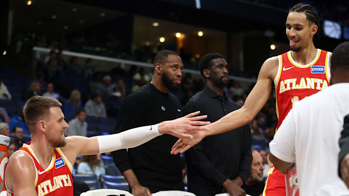 Atlanta Hawks forward Zaccharie Risacher exchanges a handshake with new Atlanta Hawks center Kristaps Porzingis during a timeout in the third quarter of Monday's preseason match at FedExForum