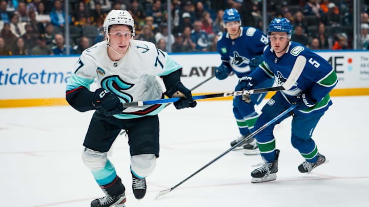 Sep 26, 2025; Vancouver, British Columbia, CAN;  Seattle Kraken forward Berkly Catton (77) and Vancouver Canucks defenseman Guillaume Brisebois (55) look for the loose puck in the second period at Rogers Arena. Mandatory Credit: Bob Frid-Imagn Images