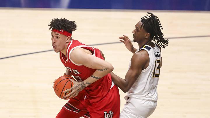 Feb 18, 2026; Morgantown, West Virginia, USA; Utah Utes forward James Okonkwo (32) grabs a rebound over West Virginia Mountaineers guard Chance Moore (13) during the second half at Hope Coliseum. Mandatory Credit: Ben Queen-Imagn Images