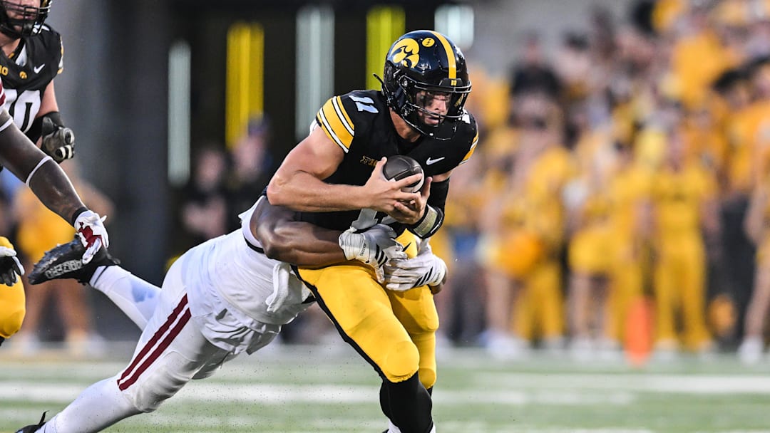 Sep 13, 2025; Iowa City, Iowa, USA; Iowa Hawkeyes quarterback Mark Gronowski (11) is tackled by Massachusetts Minutemen defensive lineman Tim Grant-Randall (11) during the first quarter at Kinnick Stadium. Mandatory Credit: Jeffrey Becker-Imagn Images