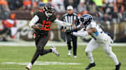 Dec 7, 2025; Cleveland, Ohio, USA; Cleveland Browns quarterback Shedeur Sanders (12) runs with the ball against Tennessee Titans linebacker Cedric Gray (33) during the second quarter at Huntington Bank Field. Mandatory Credit: Scott Galvin-Imagn Images