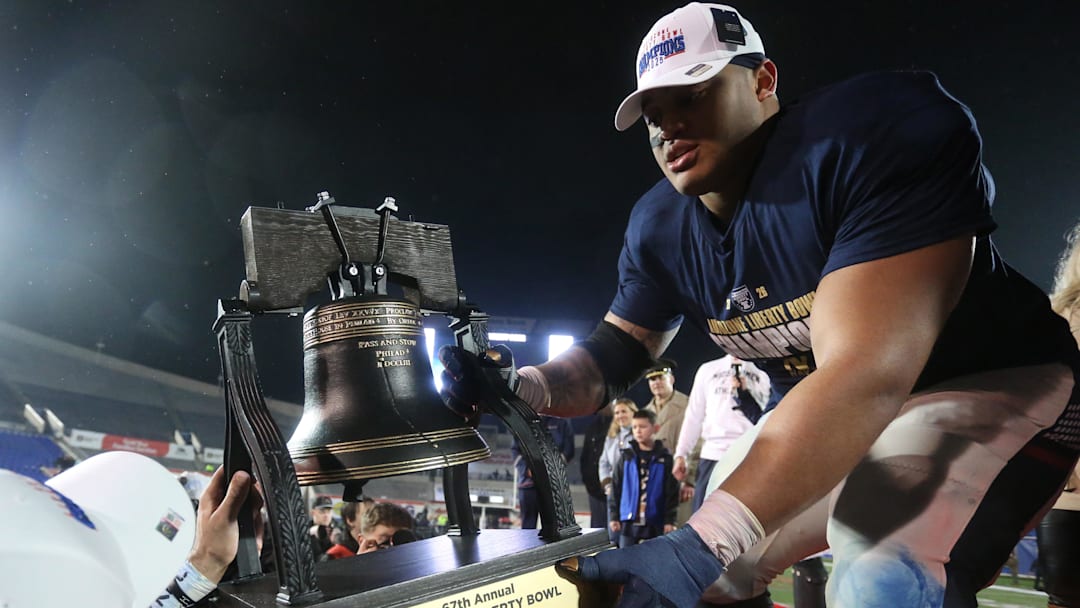 Jan 2, 2026; Memphis, TN, USA; Navy Midshipmen defensive lineman Landon Robinson (96) passes the Liberty Bell trophy off the stage after defeating the Cincinnati Bearcats in the Liberty Bowl at Simmons Bank Liberty Stadium. Mandatory Credit: Petre Thomas-Imagn Images