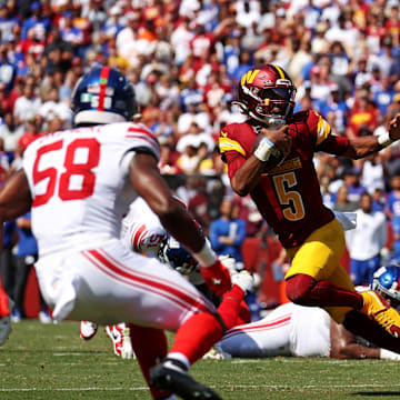 Sep 15, 2024; Landover, Maryland, USA; Washington Commanders quarterback Jayden Daniels (5) runs the ball against New York Giants safety Tyler Nubin (31) and linebacker Bobby Okereke (58) during the fourth quarter at Commanders Field.  