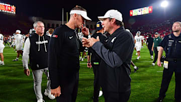 Sep 20, 2025; Los Angeles, California, USA; Southern California Trojans head coach Lincoln Riley meets with Michigan State Spartans head coach Jonathan Smith following the game at the Los Angeles Memorial Coliseum. Mandatory Credit: Gary A. Vasquez-Imagn Images
