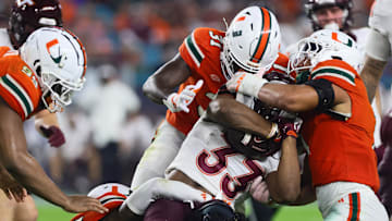 Sep 27, 2024; Miami Gardens, Florida, USA; Virginia Tech Hokies running back Bhayshul Tuten (33) runs with the football as Miami Hurricanes linebacker Wesley Bissainthe (31), linebacker Francisco Mauigoa (1) and linebacker Malik Bryant (24) pull him down during the third quarter at Hard Rock Stadium. Mandatory Credit: Sam Navarro-Imagn Images