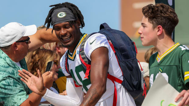 Green Bay Packers wide receiver Malik Heath (18) shares a laugh with the boy whose bike Heath is riding to practice.