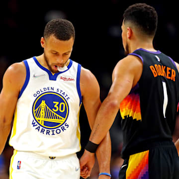 Nov 30, 2021; Phoenix, Arizona, USA; Golden State Warriors guard Stephen Curry (30) reacts with Phoenix Suns guard Devin Booker (1) during the first quarter at Footprint Center. Mandatory Credit: Mark J. Rebilas-Imagn Images