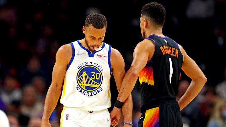 Nov 30, 2021; Phoenix, Arizona, USA; Golden State Warriors guard Stephen Curry (30) reacts with Phoenix Suns guard Devin Booker (1) during the first quarter at Footprint Center. Mandatory Credit: Mark J. Rebilas-Imagn Images