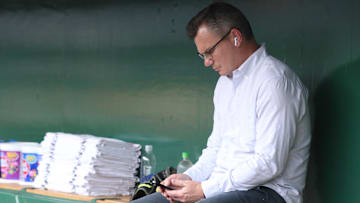 Apr 29, 2025; Pittsburgh, Pennsylvania, USA; Pittsburgh Pirates general manager Ben Cherington checks his phone in he dugout before the game against the Chicago Cubs at PNC Park. Mandatory Credit: Charles LeClaire-Imagn Images